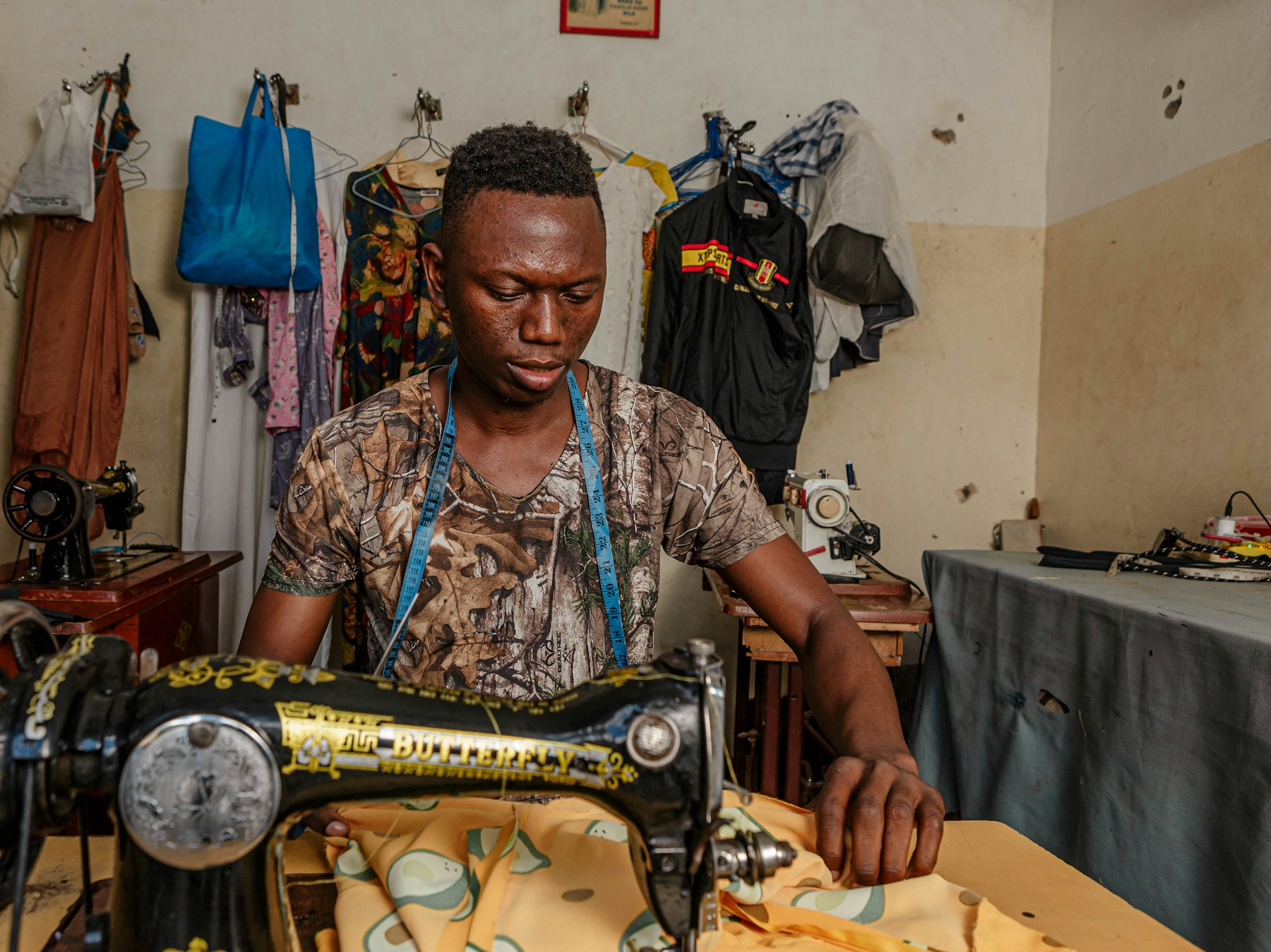 A tailor at his sewing machine, guiding printed cloth under the needle